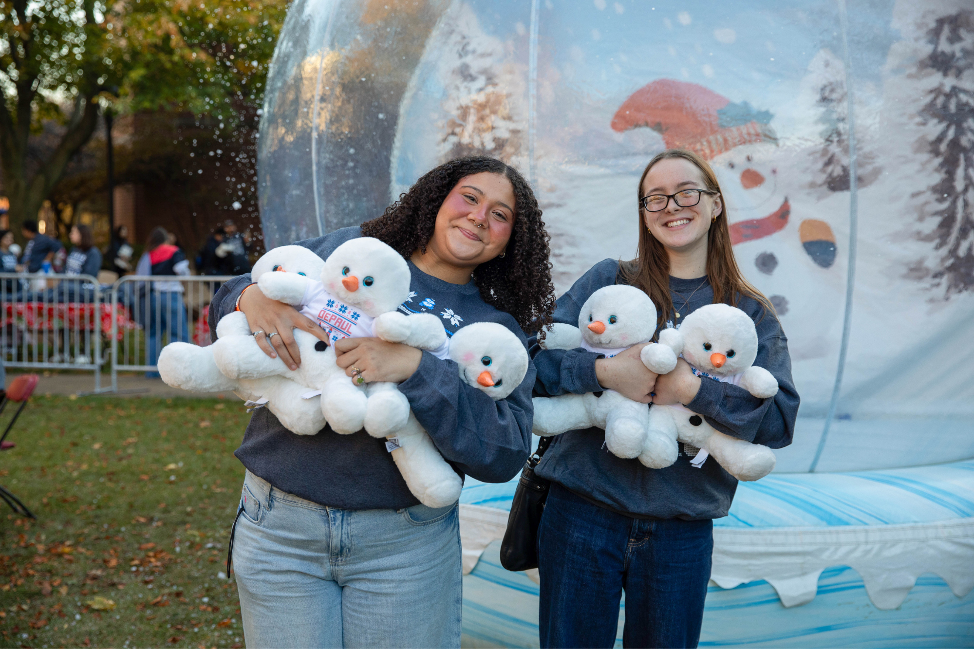 Two women smiling and holding snowman plushies